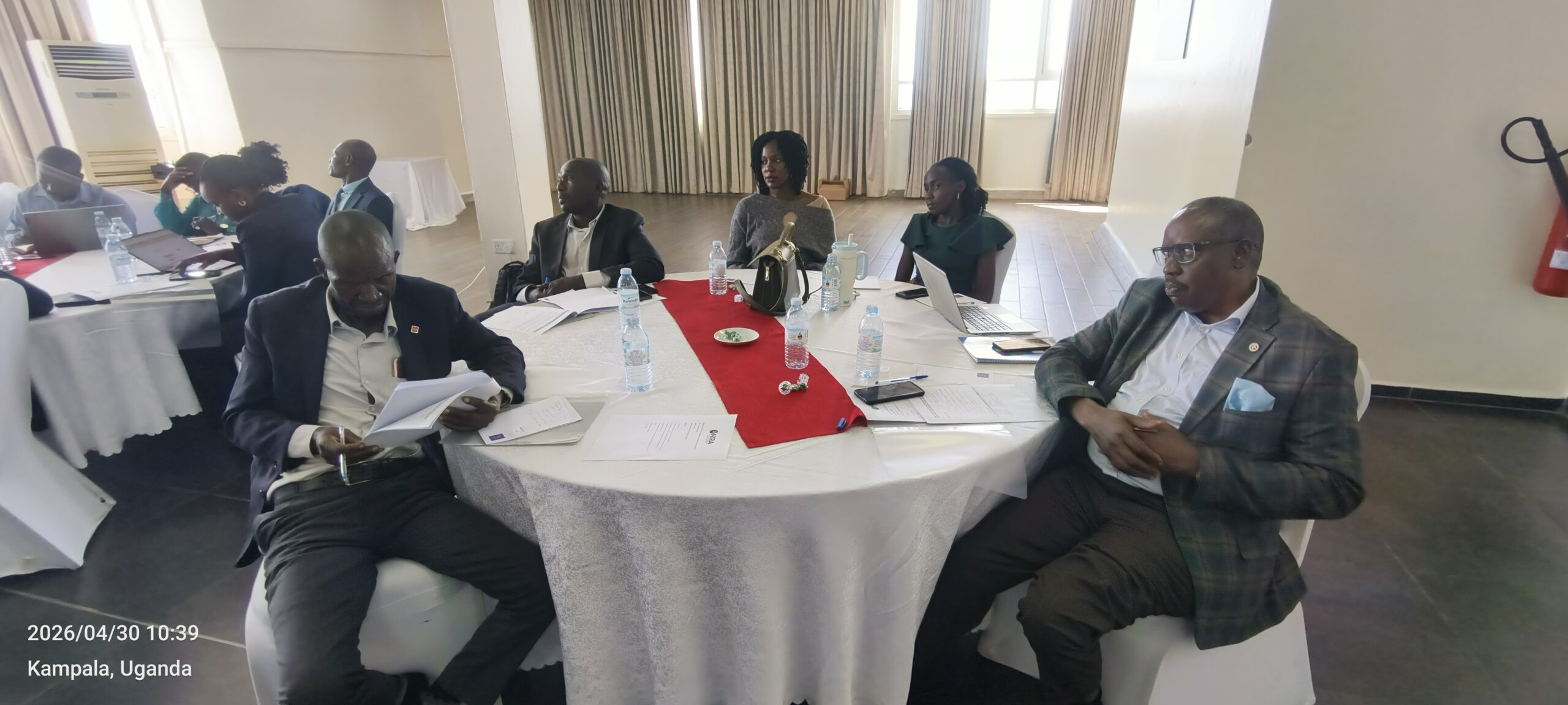 Business meeting in Kampala, Uganda, around a round table with laptops, papers, and water bottles on the table.